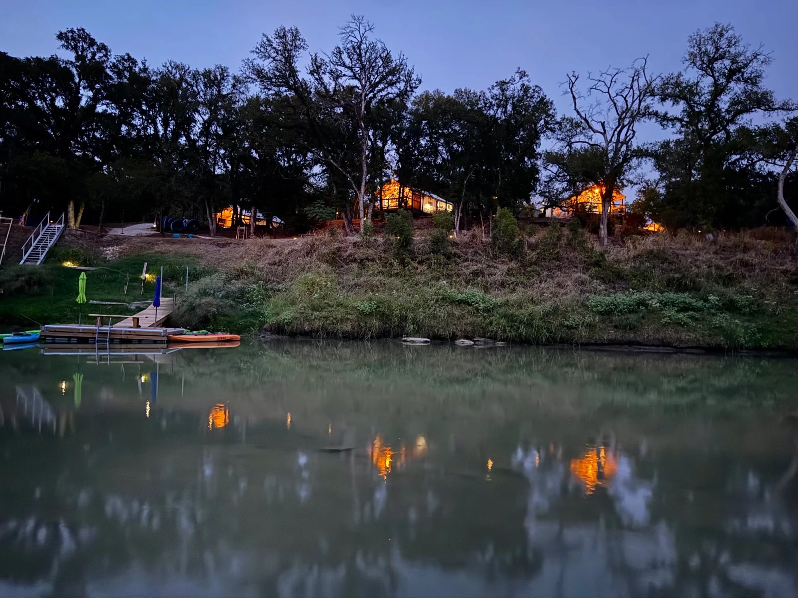 Tents glowing above the river at dusk